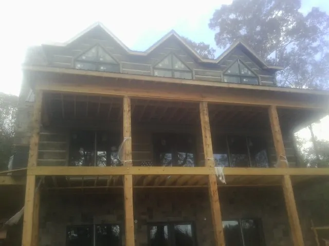 Dormers and porch framing on a large log home under construction — Roof Coating work by our crew in Pickens